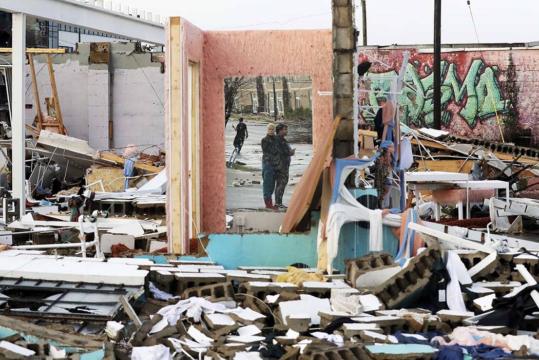 People are reflected in a mirror of a building destroyed by storms Tuesday, March 3, 2020, in N ...