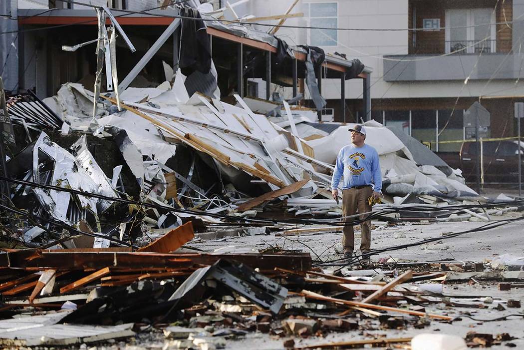 A man looks over buildings destroyed by storms Tuesday, March 3, 2020, in Nashville, Tenn. Torn ...
