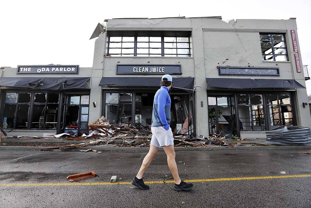 A man walks by buildings destroyed by storms Tuesday, March 3, 2020, in Nashville, Tenn. Tornad ...