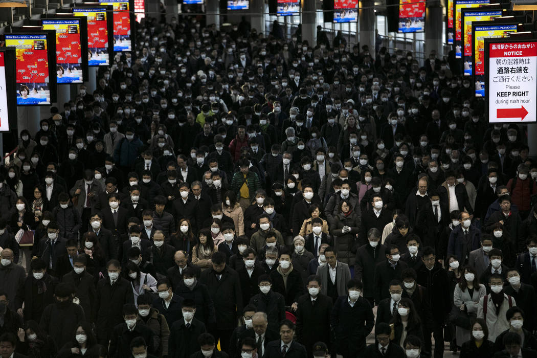 A large crowd wearing masks commutes through Shinagawa Station in Tokyo, Tuesday, March 3, 2020 ...