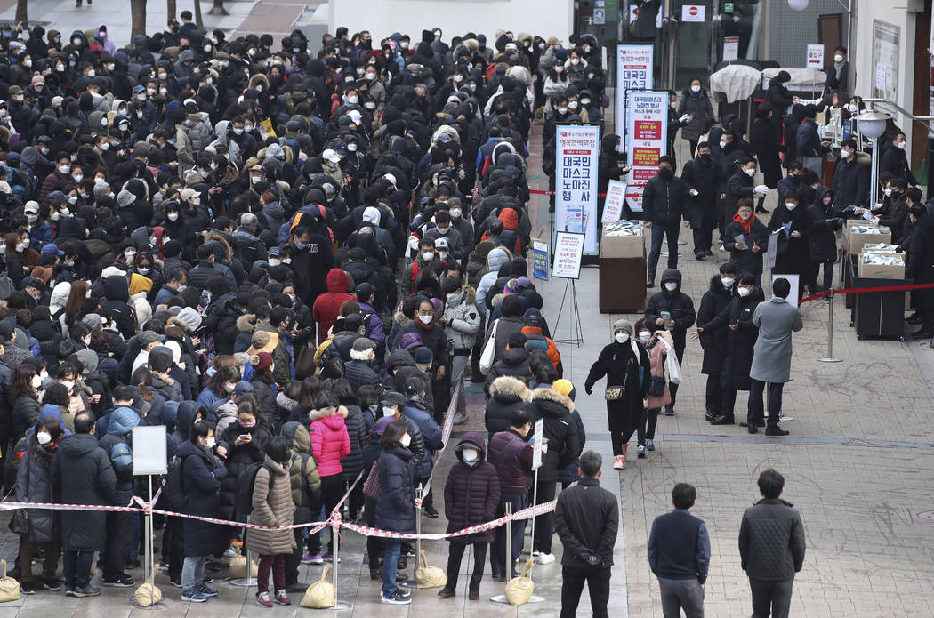 Hundreds of people line up to buy face masks to protect themselves from the coronavirus in fron ...