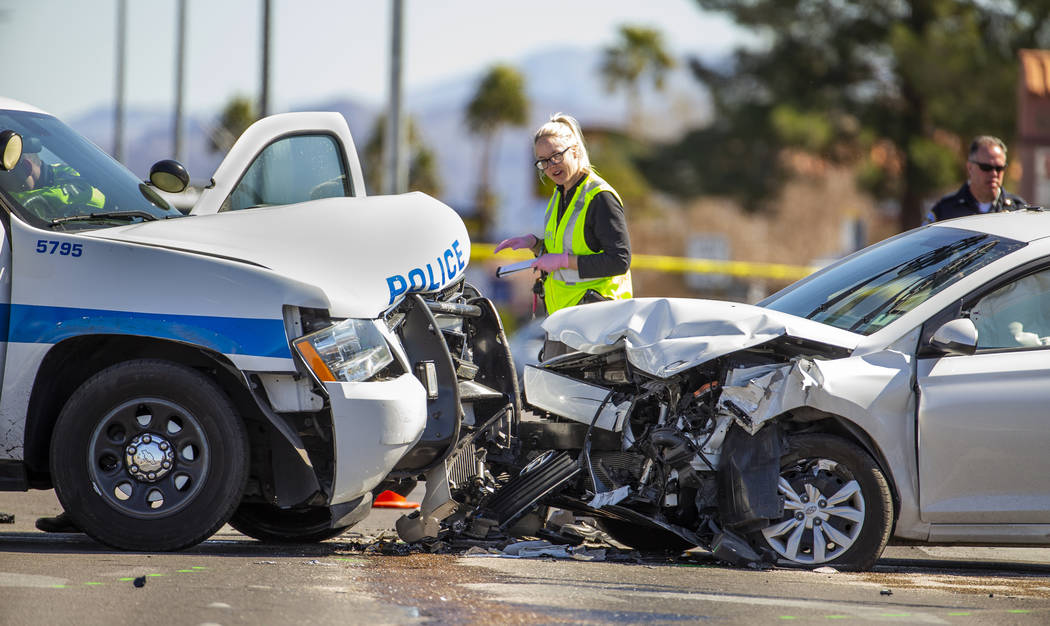 An investigations team works the accident scene where a Henderson Police vehicle was struck whi ...