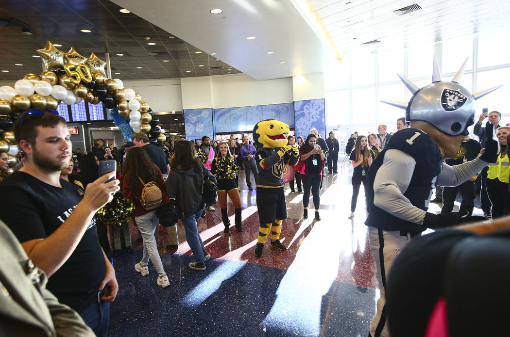 Golden Knights mascot Chance and Raiders mascot Raider Rusher welcome passengers deplaning from ...
