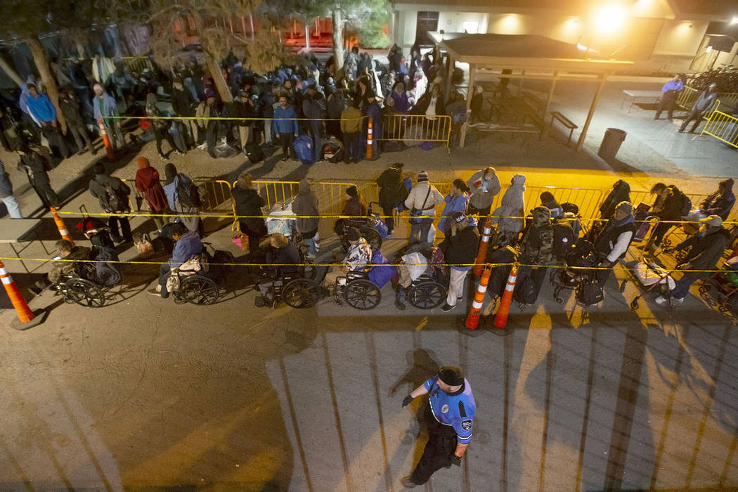 People wait in line to check in and get a sleeping mat at the Courtyard Homeless Resource Cente ...