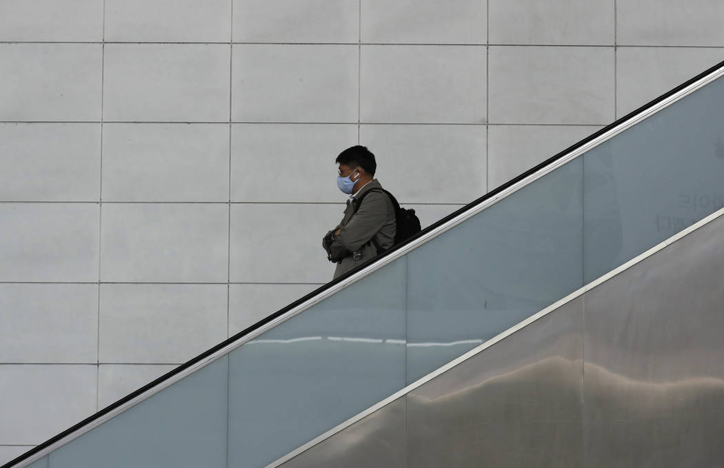 A man wearing a face mask rides the escalator in Seoul, South Korea, Wednesday, March 4, 2020. ...