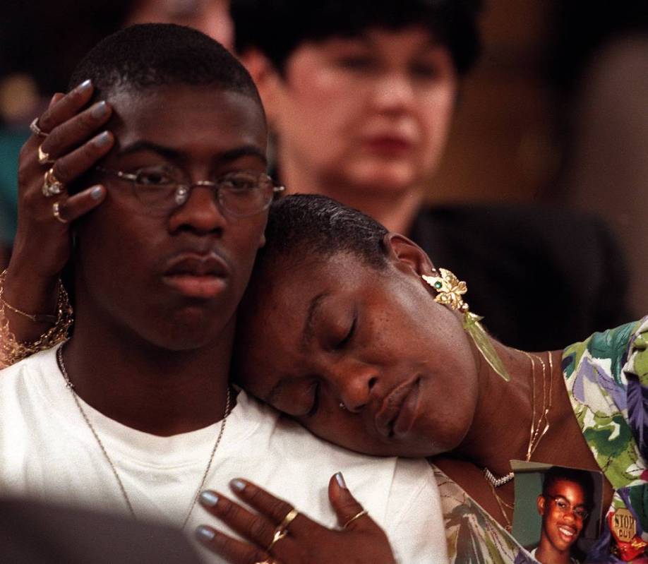 Brigitte Smith embraces her son T.J., 15 with a picture of her dead son Anthony, 14, strapped t ...