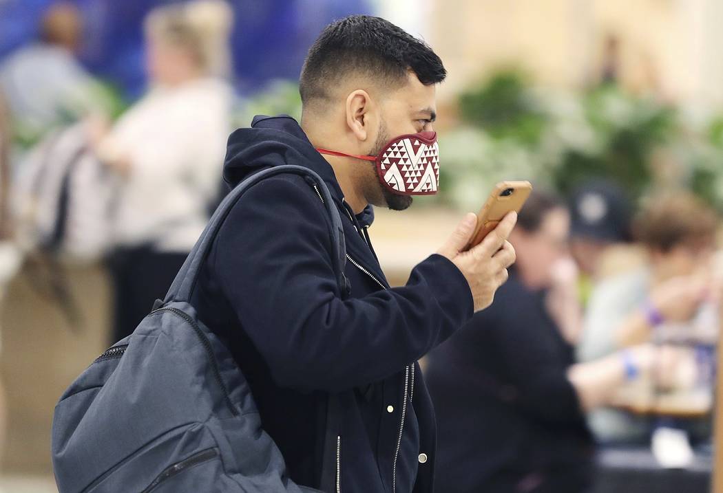 Airline passengers wear masks in the terminal area of Orlando International Airport on Wednesda ...