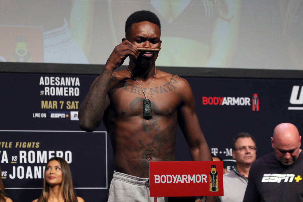 UFC middleweight champion Israel Adesanya smells a cigar on the scale during the UFC 248 ceremo ...