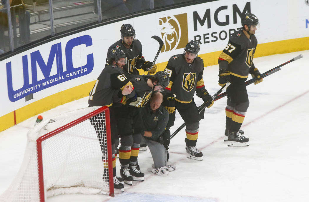 Golden Knights' Cody Glass (9) is escorted off the ice with the help of teammates during the th ...