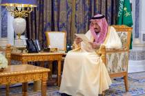 Saudi King Salman reads a document as he receives two newly appointed Saudi ambassadors at his ...
