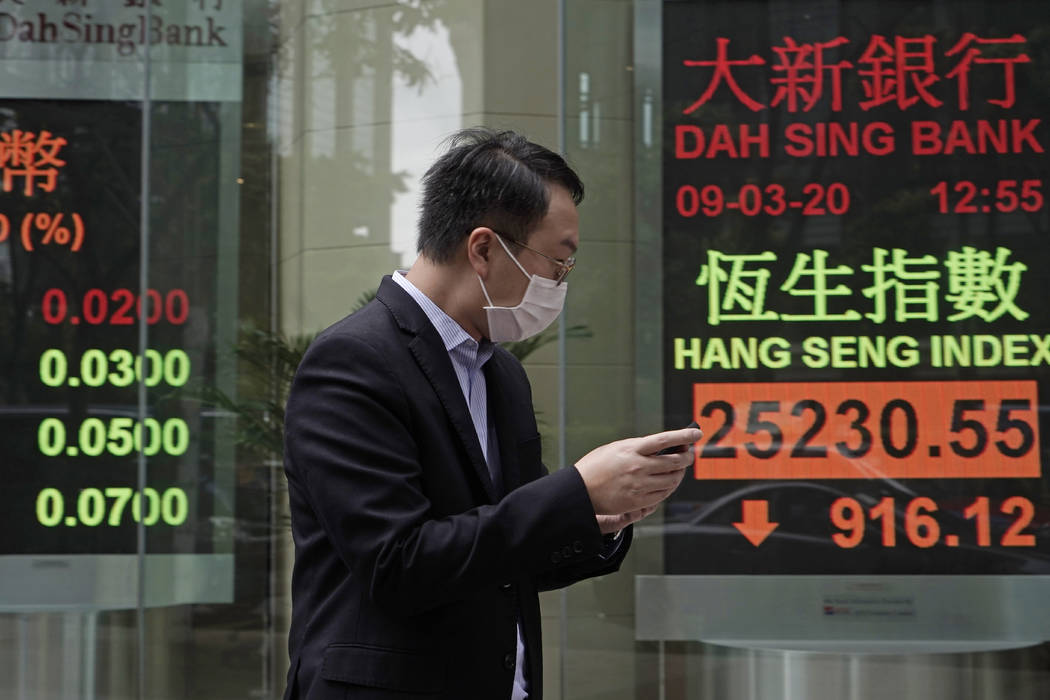 A man walks past an electronic board showing Hong Kong share index outside a local bank in Hong ...