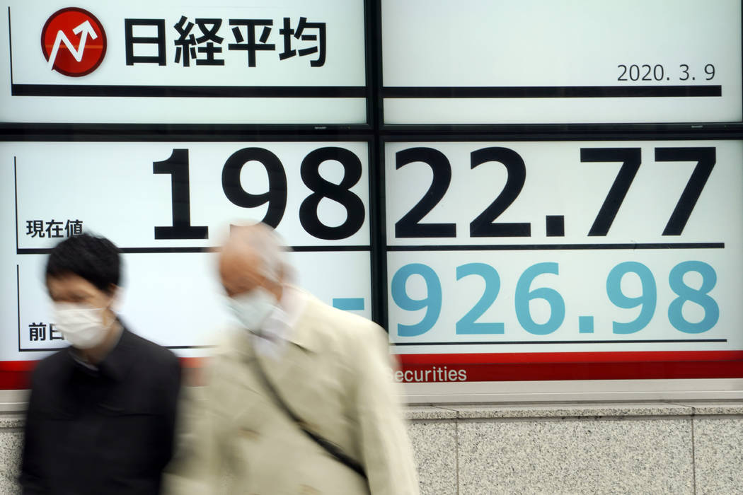 Men walk past an electronic stock board showing Japan's Nikkei 225 index at a securities firm i ...