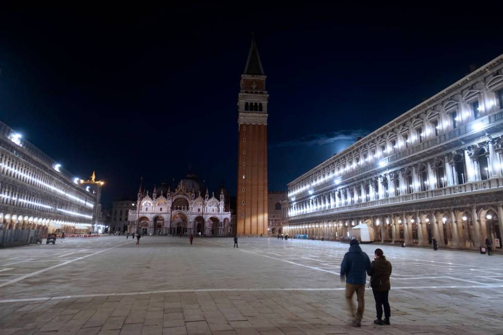 People walk in an almost empty St. Mark's Square in Venice, Italy, Monday, March 9, 2020. Itali ...