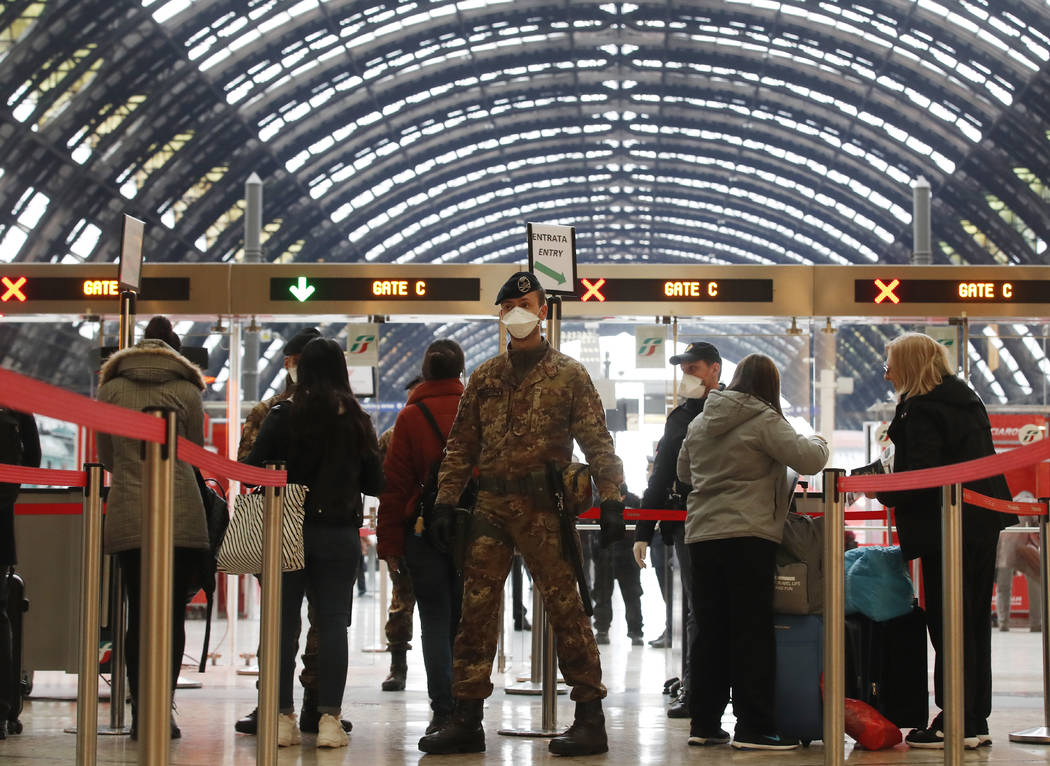 Police officers and soldiers check passengers leaving from Milan main train station, Italy, Mon ...