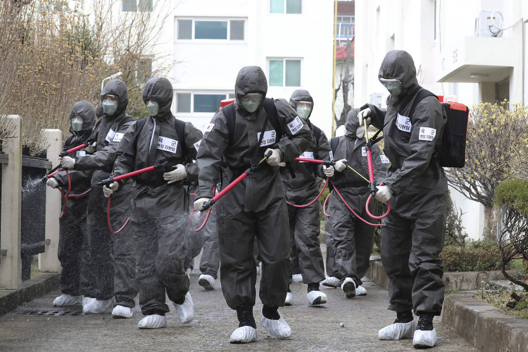 Army soldiers spray disinfectant as a precaution against a new coronavirus at an apartment buil ...