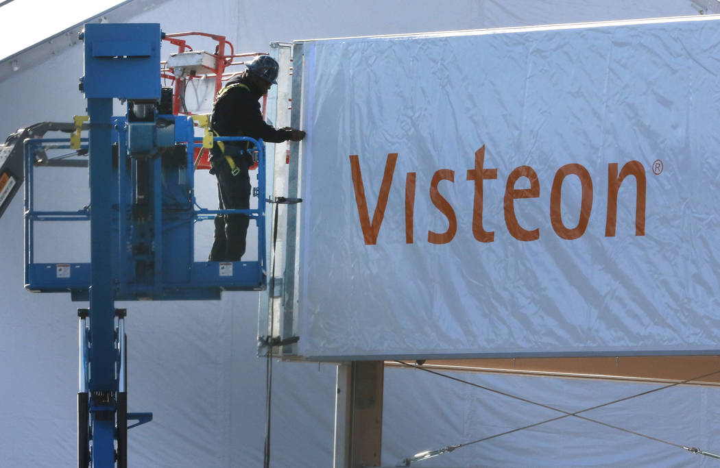 A worker from Pavillon Event Service installs the Visteon's, a global technology company, booth ...
