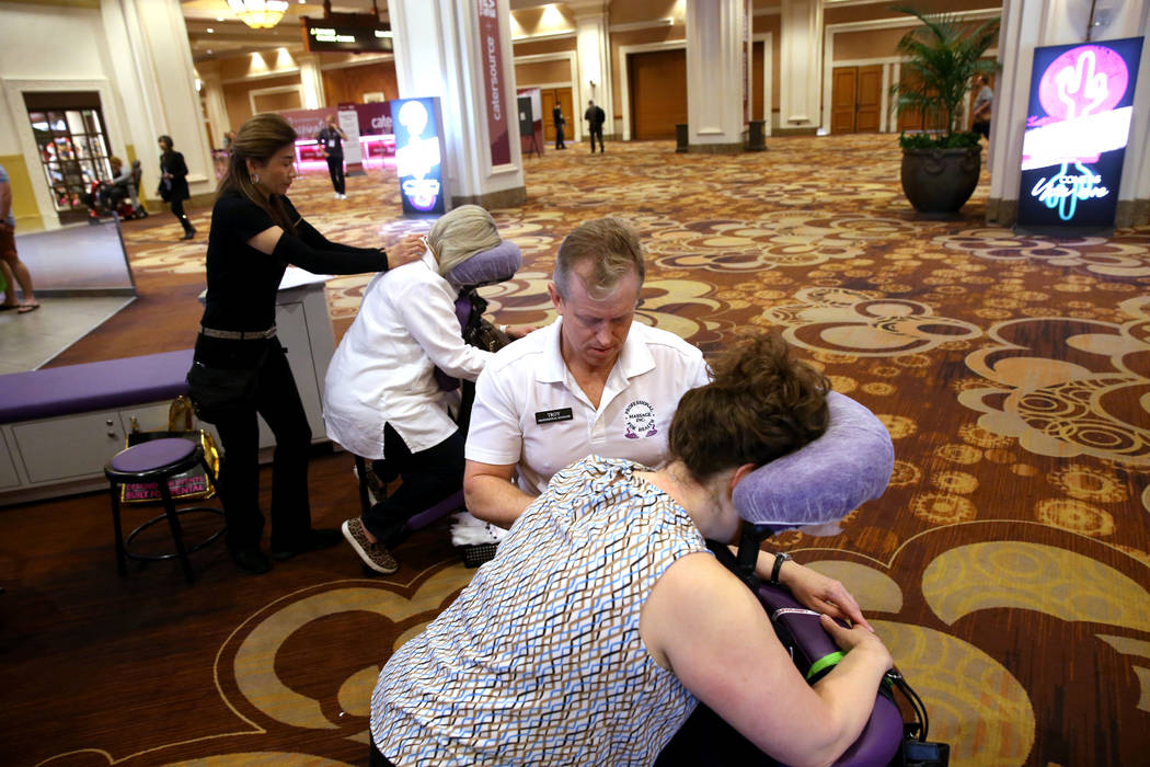Las Vegas massage therapist Ling Cooley, left, works on Laura Hendrix of Waco, Texas, while Tro ...