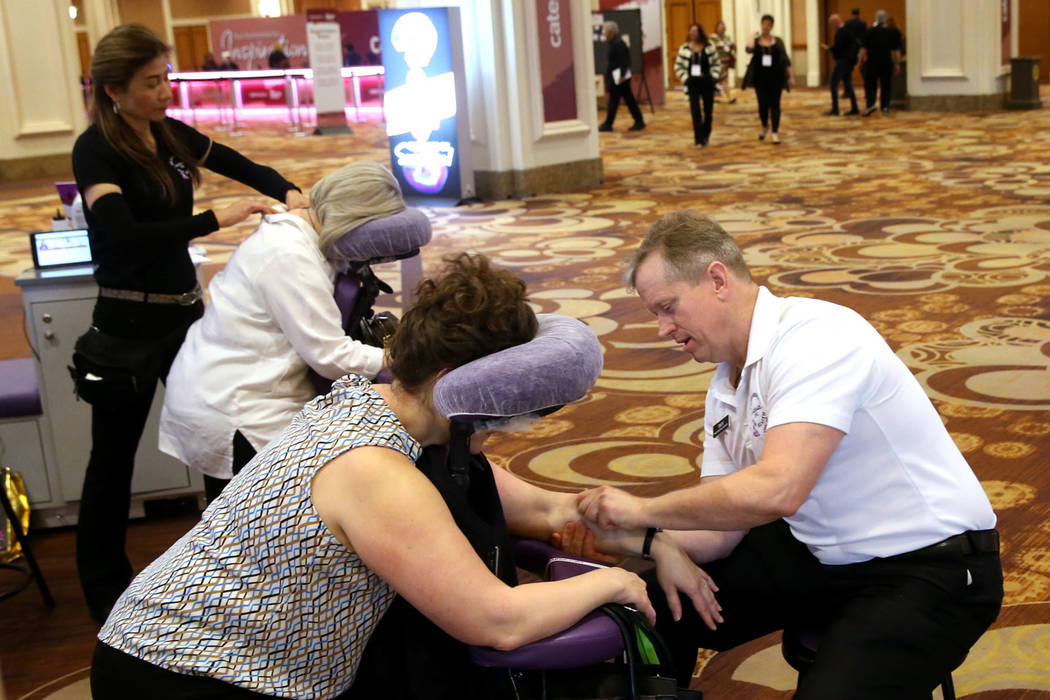 Las Vegas massage therapist Ling Cooley, left, works on Laura Hendrix of Waco, Texas, while Tro ...