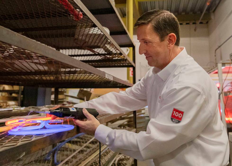 Argon gas lights up a glass tube shown by Yesco's senior vice president Jeff Young during a tou ...