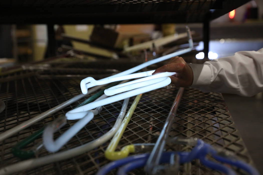 Argon gas lights up a glass tube shown by YESCO's senior vice president Jeff Young during a tou ...