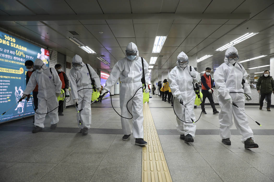 Workers wearing protective gears disinfect as a precaution against the new coronavirus at the s ...