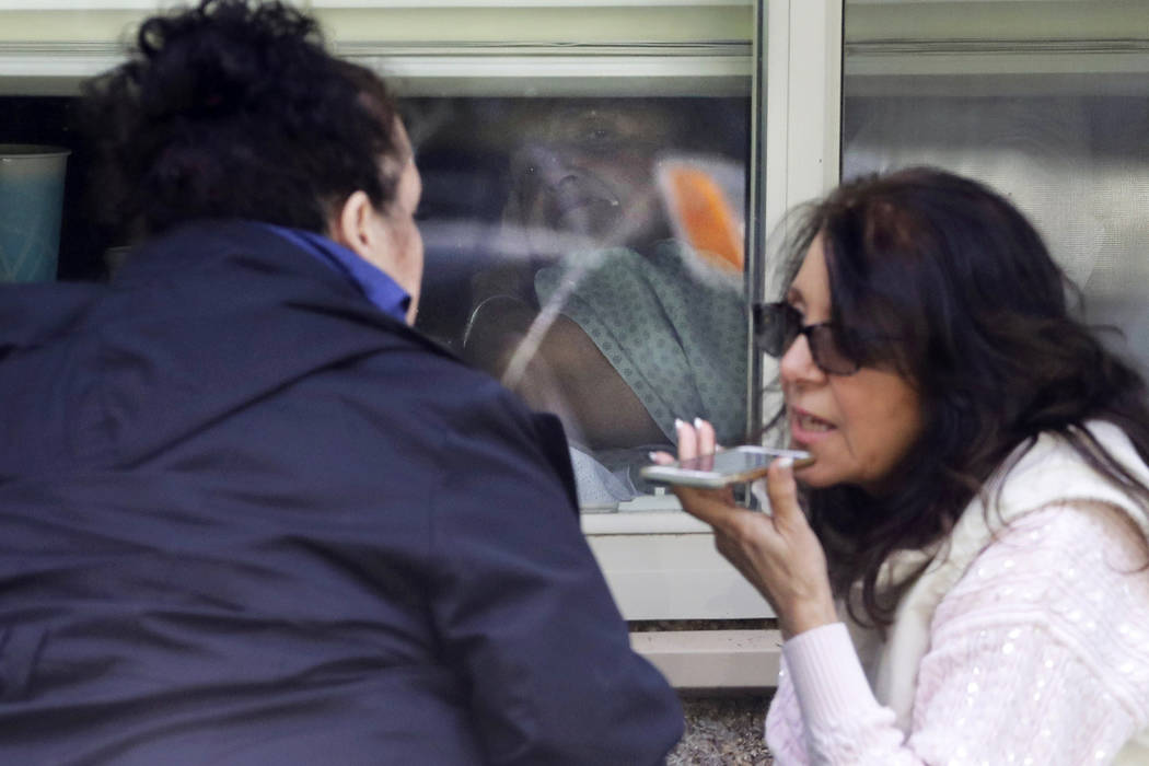 Bridget Parkhill, left, and her sister, Carmen Gray, right, talk on a phone as they visit throu ...