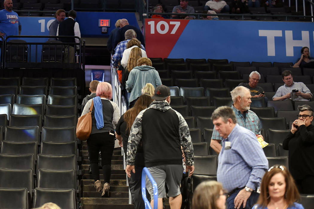 Basketball fans leave Chesapeake Energy Arena after it is announced that an NBA basketball game ...