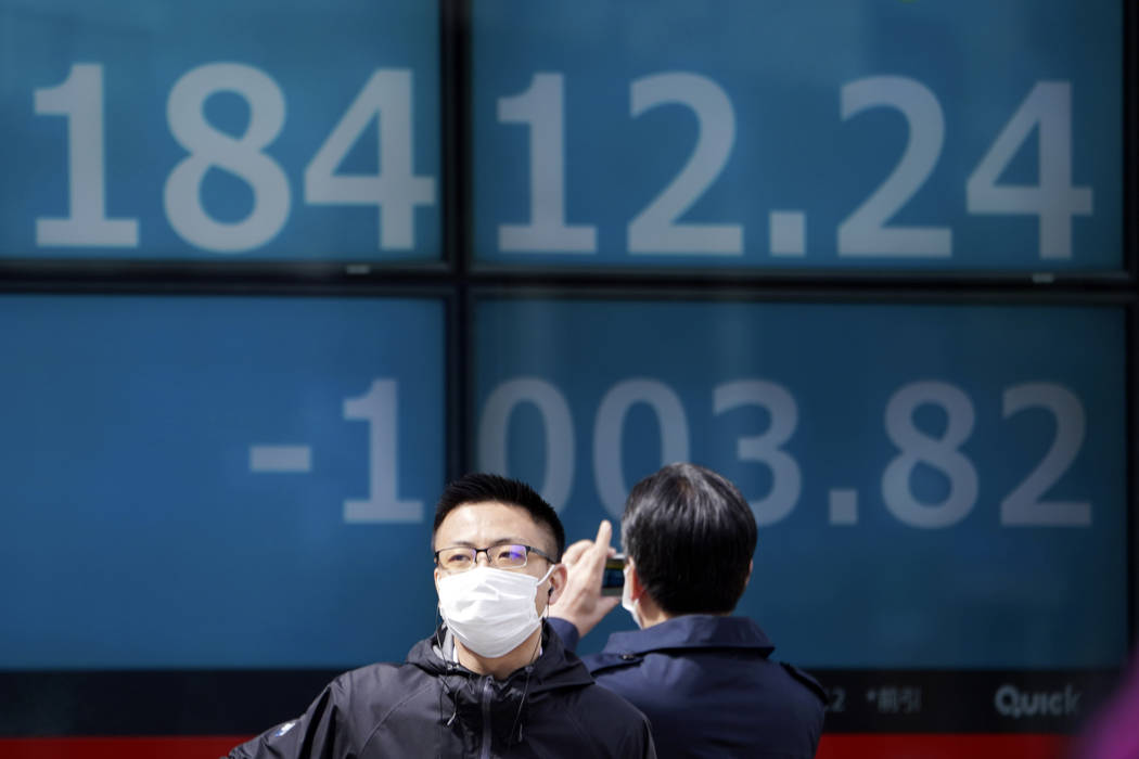Men stand in front of an electronic stock board showing Japan's Nikkei 225 index at a securitie ...