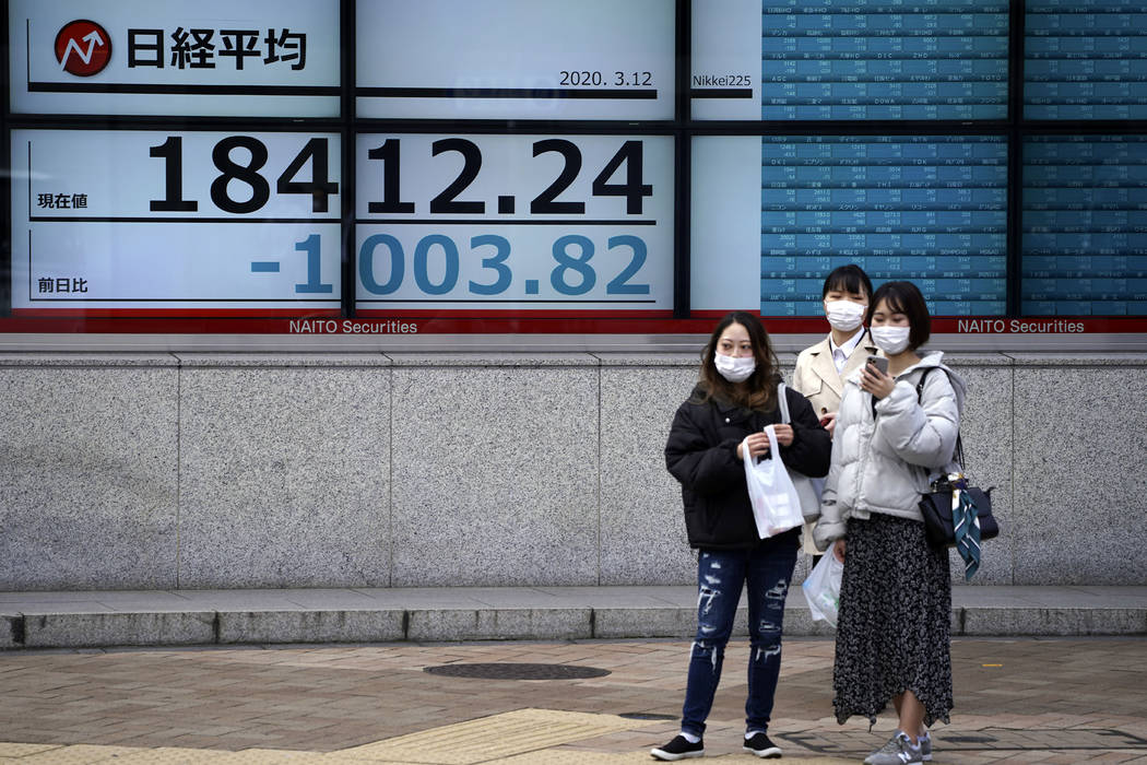Women stand in front of at an electronic stock board showing Japan's Nikkei 225 index at a secu ...