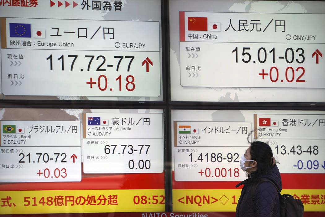 A woman looks at an electronic stock board showing foreign exchange rates at a securities firm ...