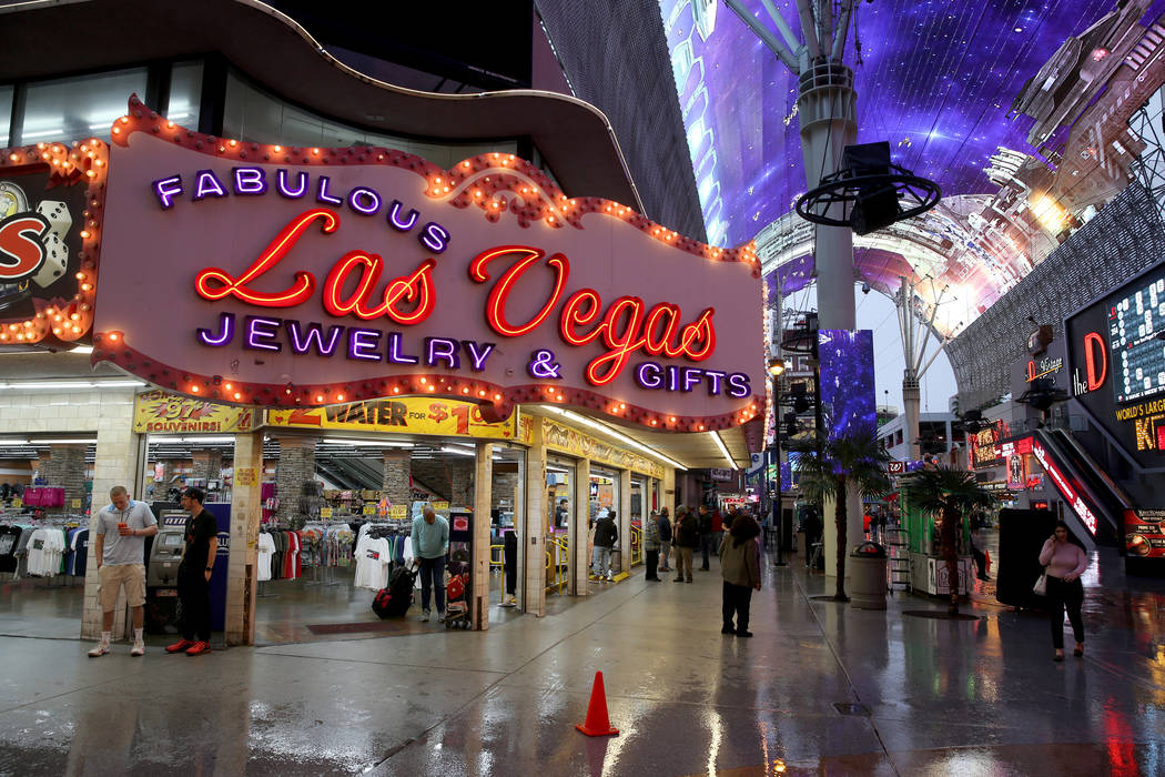 People take shelter from a light rain at the Fremont Street Experience in downtown Las Vegas Th ...