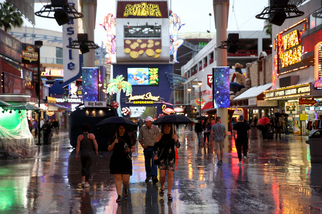 People walk in a light rain at the Fremont Street Experience in downtown Las Vegas Thursday, Ma ...