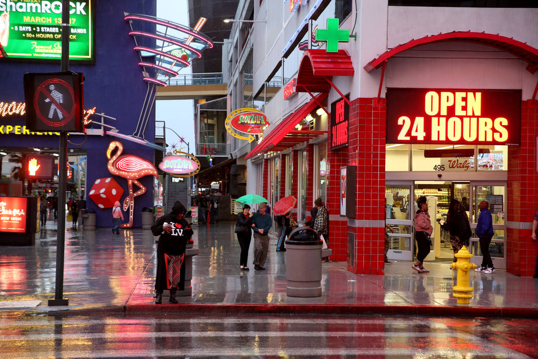 People walk in a light rain at the Fremont Street Experience in downtown Las Vegas Thursday, Ma ...