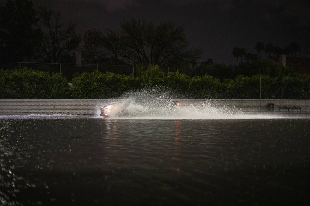 A vehicle passes through a flooded section of Eastern Avenue after heavy rain on Thursday, Marc ...