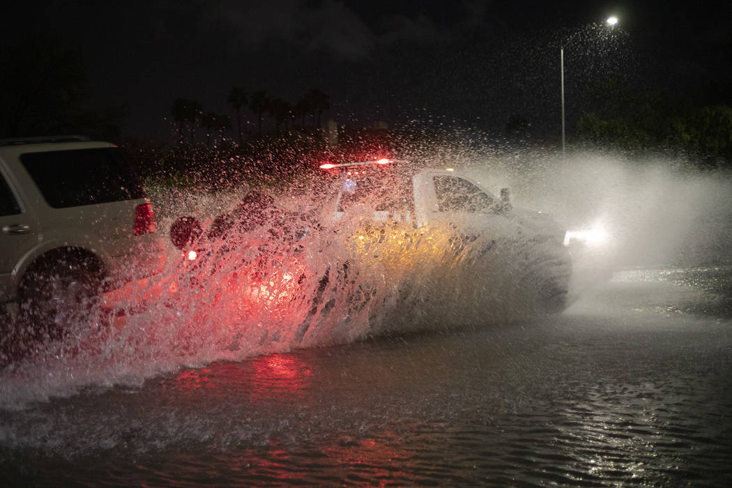 A truck towing another vehicle passes through a flooded section of Eastern Avenue after heavy r ...