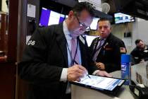 Traders Edward Curran, left, and Jonathan Mueller work on the floor of the New York Stock Excha ...