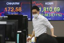 A currency trader wearing a face mask watches monitors at the foreign exchange dealing room of ...