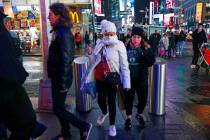 Tourists, including one using a scarf to protect her face against coronavirus in spite of relat ...