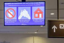 A slide flashes on a screen reminding passengers to wash hands often at the McCarran Internatio ...