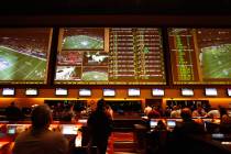 Prop bets are displayed above the crowd before the start of Super Bowl in the sports book at Re ...