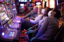 Gamblers wear masks and gloves in the midst of the coronavirus pandemic at Planet Hollywood on ...