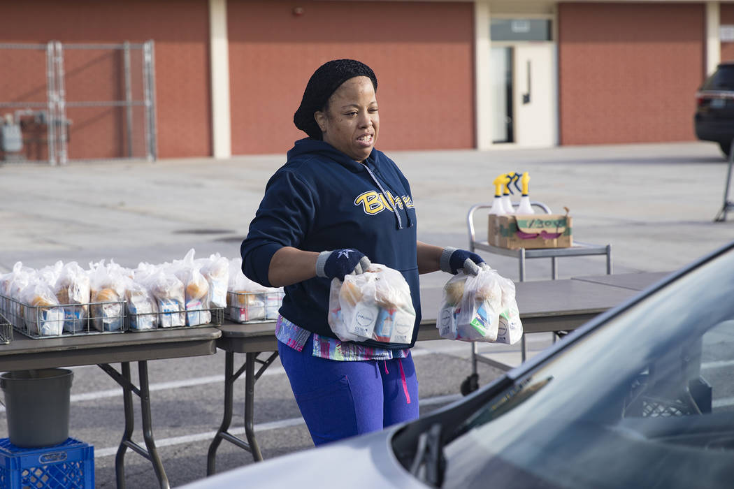 A Clark County School District employee hands out breakfast and lunch packages to families at C ...