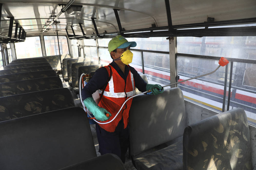 A worker disinfects a police bus as a precaution against COVID-19 in New Delhi, India, Monday, ...