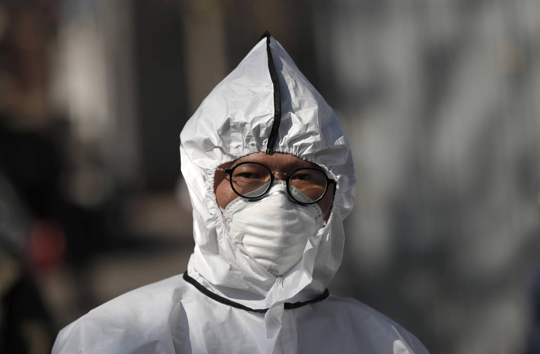 A worker wearing a protective gear prepares to spray disinfectant as a precaution against the n ...