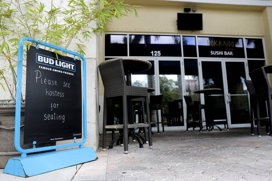 A sign is placed at a deserted at Hokkaido sushi bar, Monday, March 16, 2020, in Jupiter, Fla. ...