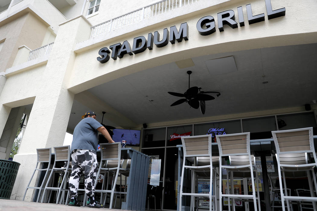 A person stands near empty seats at Stadium Grill, Monday, March 16, 2020, in Jupiter, Fla. The ...