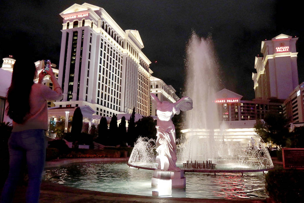 A woman takes a photo of Caesars Palace on the Las Vegas Strip, Saturday, March 14, 2020. (Elle ...