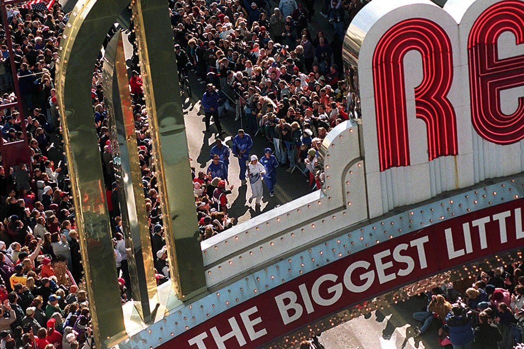 Jessica Young, in white, carries the Olympic torch toward the Reno Arch, Monday, Jan. 21, 2002, ...