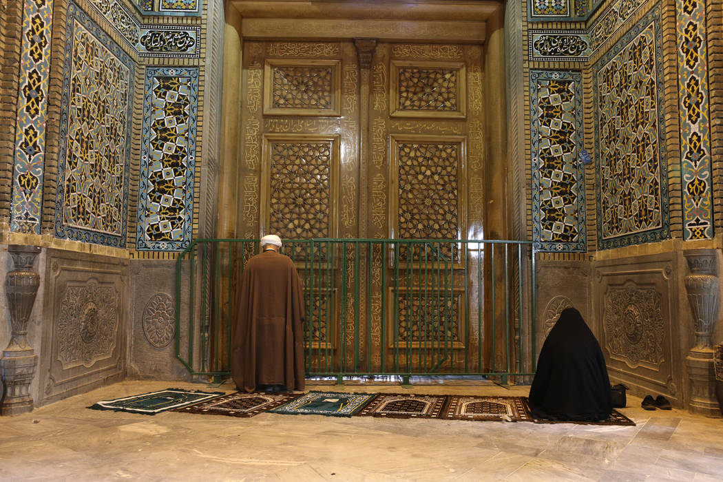 A cleric and a woman pray behind a closed door of Masoume shrine in the city of Qom, some 80 mi ...
