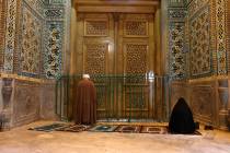 A cleric and a woman pray behind a closed door of Masoume shrine in the city of Qom, some 80 mi ...